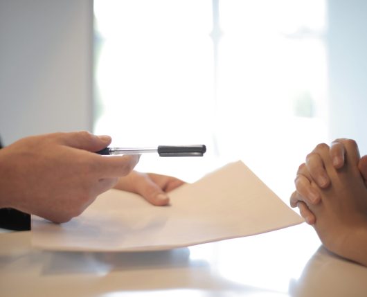 Man pointing a pen towards the person sitting in front of him